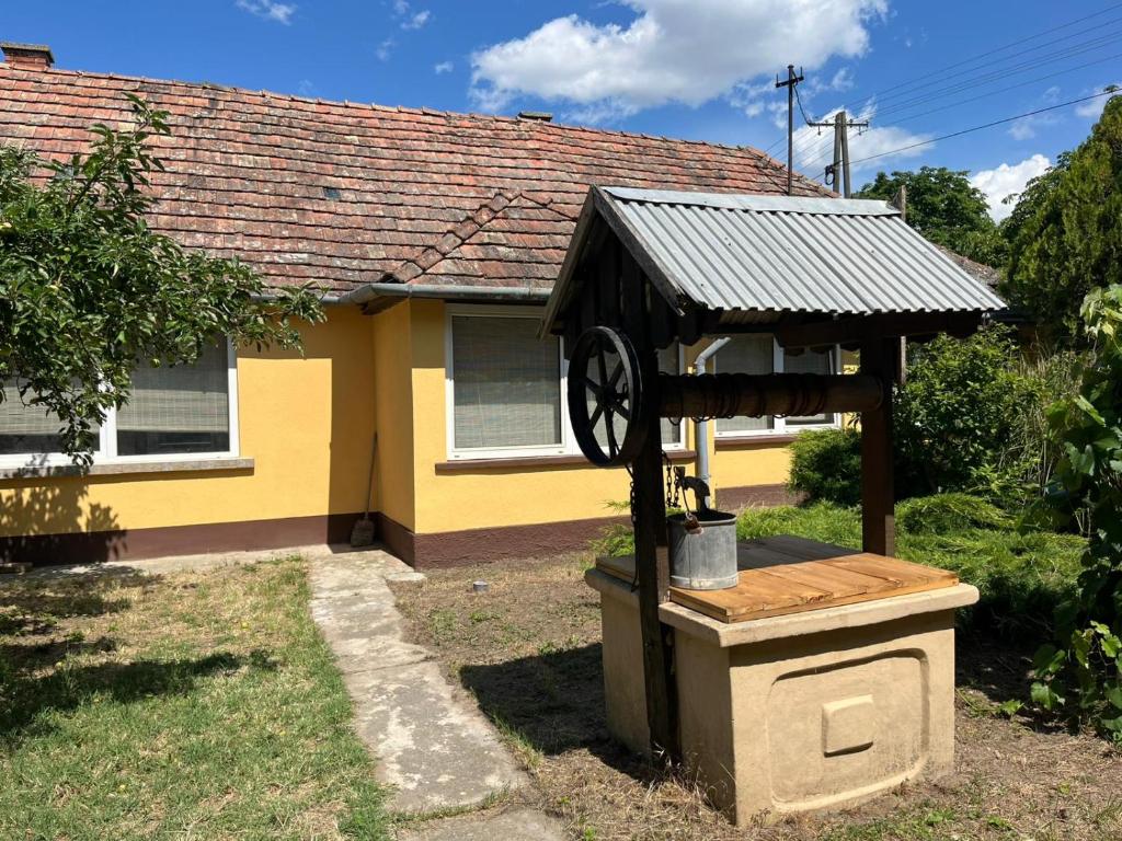 a building with a clock in front of a house at Tengelice-ház in Réde