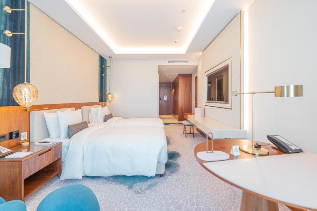 ドーハにあるAbesq Doha Hotel and Residences, an IHG Hotelのベッドと机があるホテルの部屋