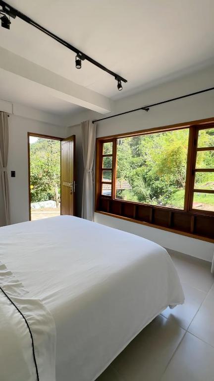 a bedroom with a large white bed and windows at Hotel Boutique Albania in Otanche