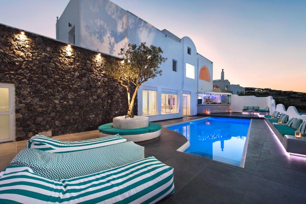 a villa with a swimming pool and lounge chairs at Gianna Suites in Fira