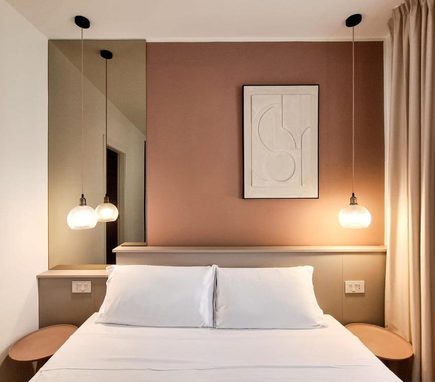 una camera da letto con un letto con due luci sopra di Hotel Lauri a Macerata