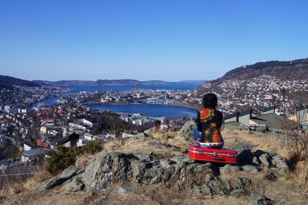 a person sitting on top of a mountain overlooking a city at Bergen Hostel Montana in Bergen