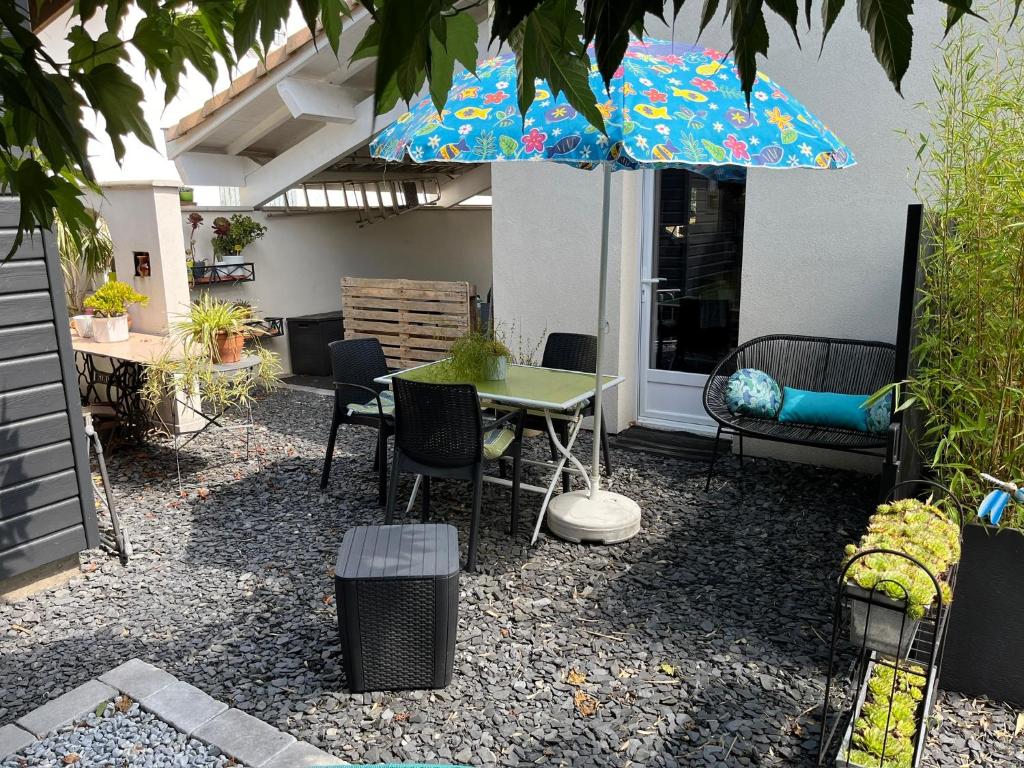 un patio avec une table, des chaises et un parasol dans l'établissement Pause relax à Mont de Marsan, à Mont-de-Marsan