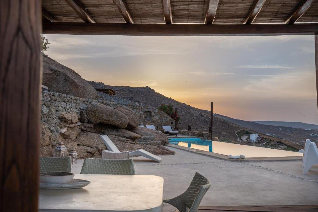 a patio with a table and chairs and a pool at Mykonos Mint Villa - Sofia in Kalafatis