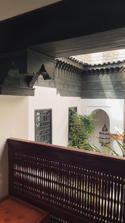 - un banc en bois dans une chambre avec des photos sur le mur dans l'établissement Dar Assiya, à Marrakech