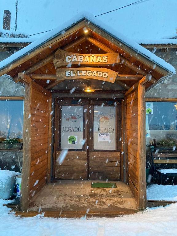 a wooden building with a sign on it in the snow at Cabañas El Legado in Los Molles