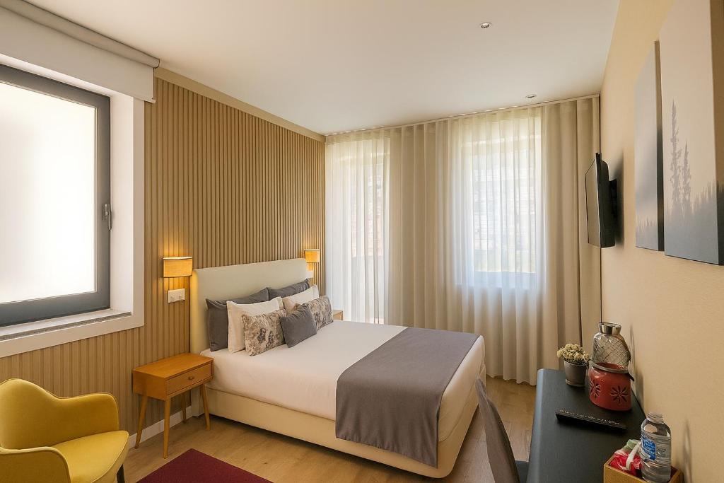 a hotel room with a bed and a yellow chair at MyTrip Porto in Matosinhos