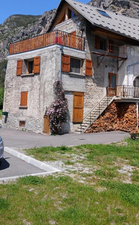 - un bâtiment en pierre avec des portes en bois et un balcon dans l'établissement Maison de village, à La Roche-de-Rame