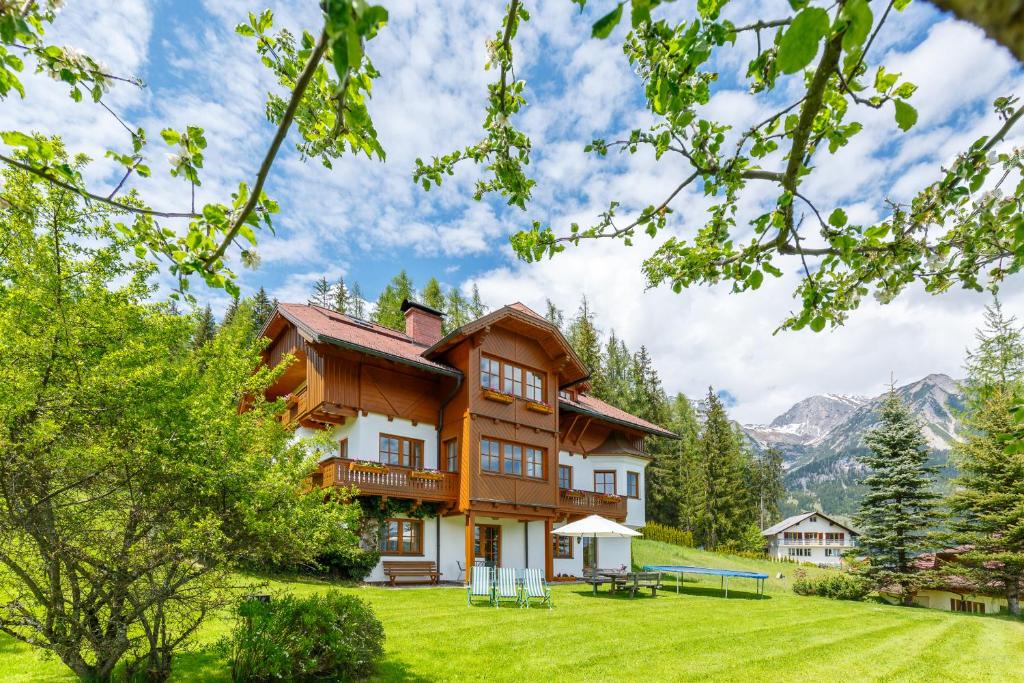 una casa su una collina con montagne sullo sfondo di Landhaus Birgbichler - Apartments mit Bergblick inklusive Sommercard a Ramsau am Dachstein