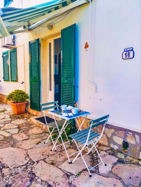 a table and chairs in front of a building with green shutters at Casina Tecla in Cavo