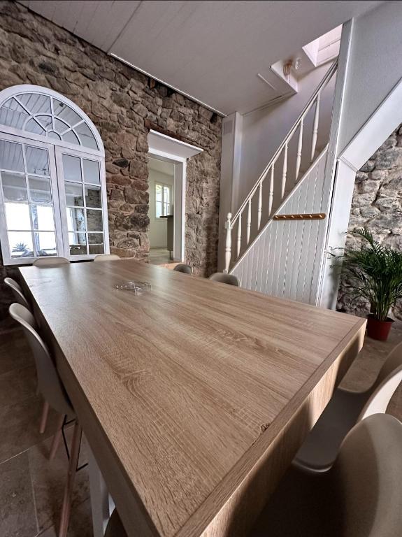 Cette chambre dispose d'une grande table en bois et d'un mur en pierre. dans l'établissement Maison familiale centre ville, à Lamastre