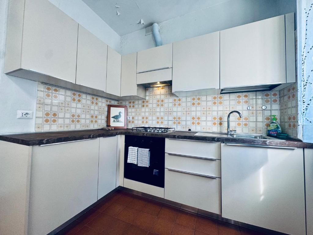 Una cocina con gabinetes blancos y un fregadero. en Bilocale Riccione sul Mare a Riccione, en Riccione
