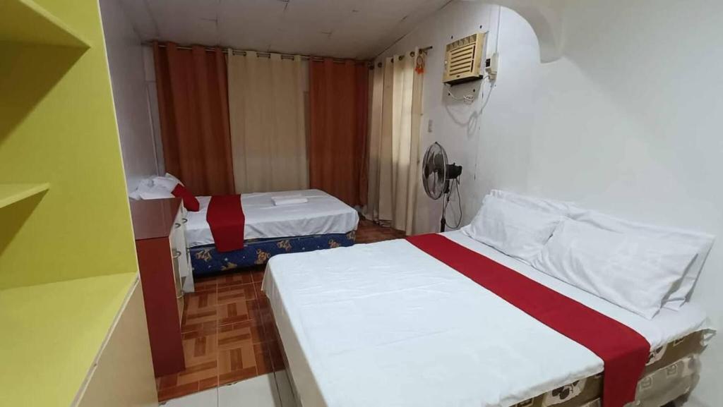 a small room with two beds and a fan at Cozy Home in Dadiangas, General Santos City - Perfect for Families 
