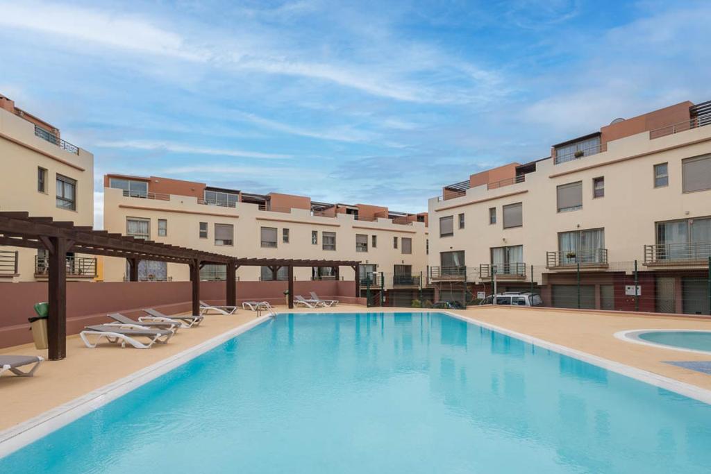 a large swimming pool in a building with chairs at Lightbooking Costa Antigua Fuerteventura in Costa de Antigua
