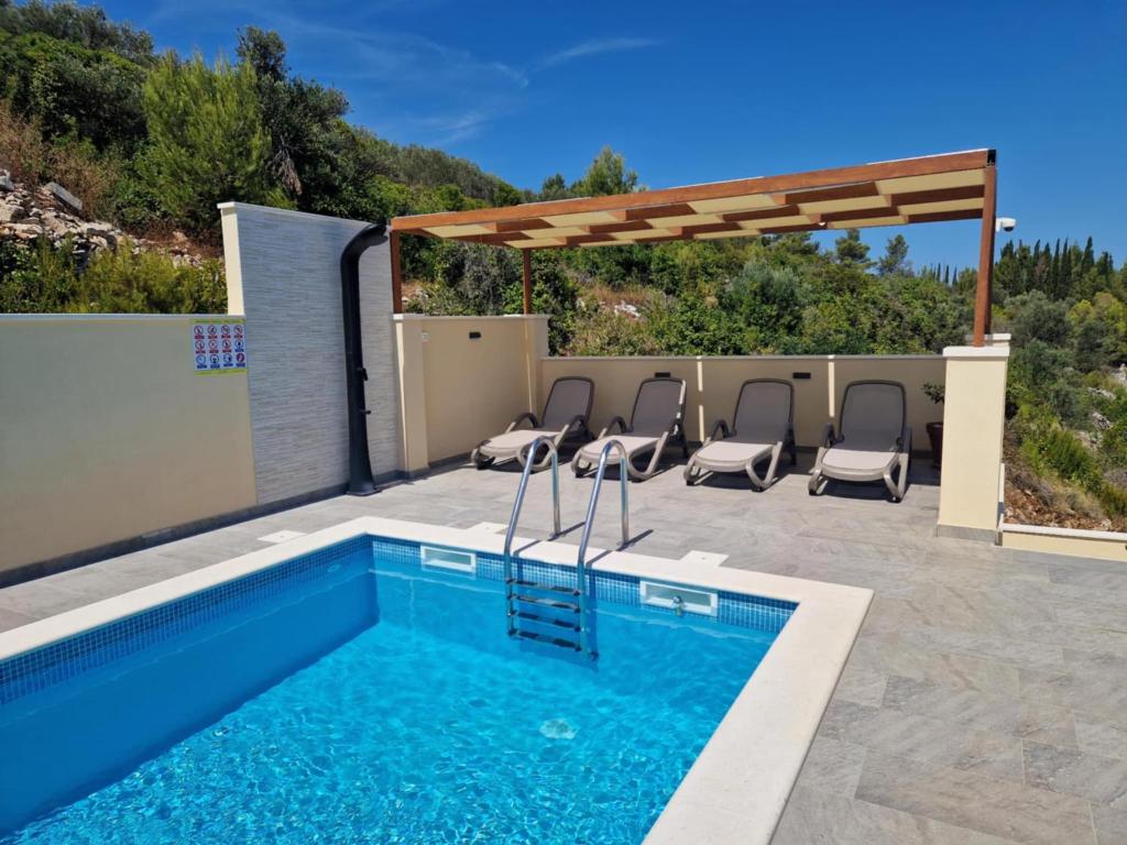 a swimming pool with chairs and a pergola at Apartman Mimi in Prigradica
