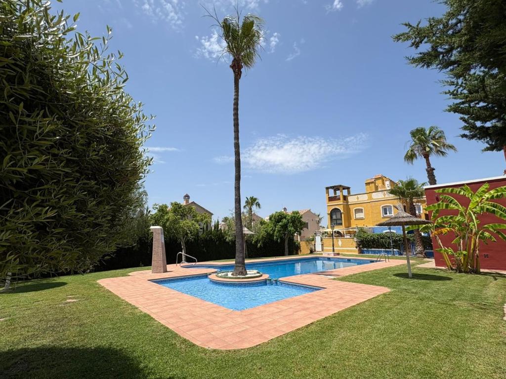 a swimming pool in a yard with a palm tree at Ideal pool Bungalow HMWY in Torrevieja