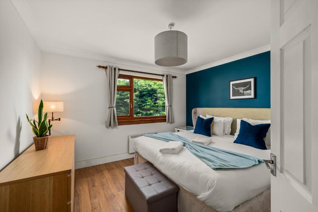 a bedroom with a large bed with blue walls at Rivendell - Cosy Countryside Retreat in Rattray