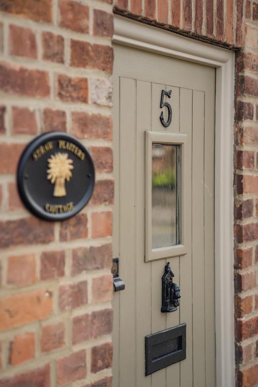 a sign on a brick wall next to a door at Straw Plaiters Cottage in Wendover