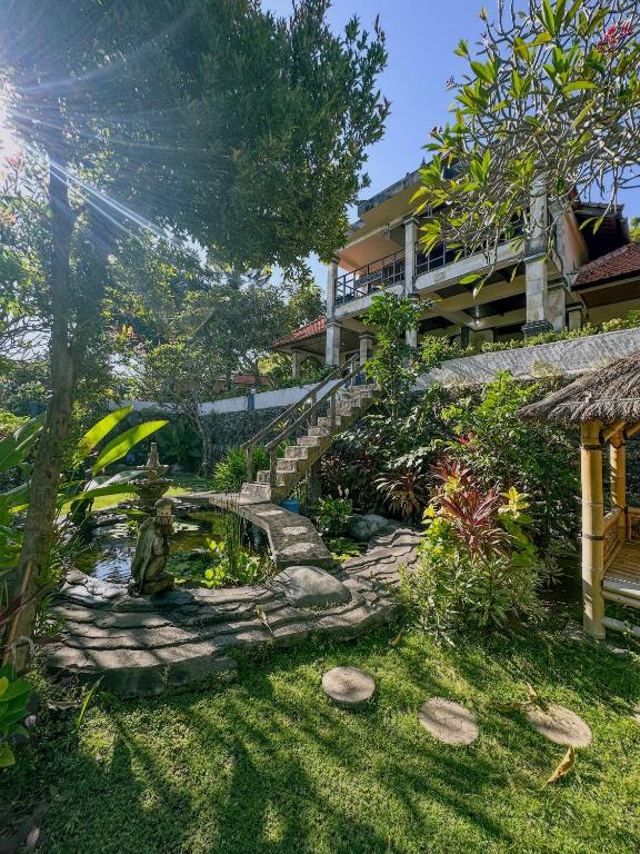 a garden with a pond in front of a building at Dejaviews Resort in Singaraja