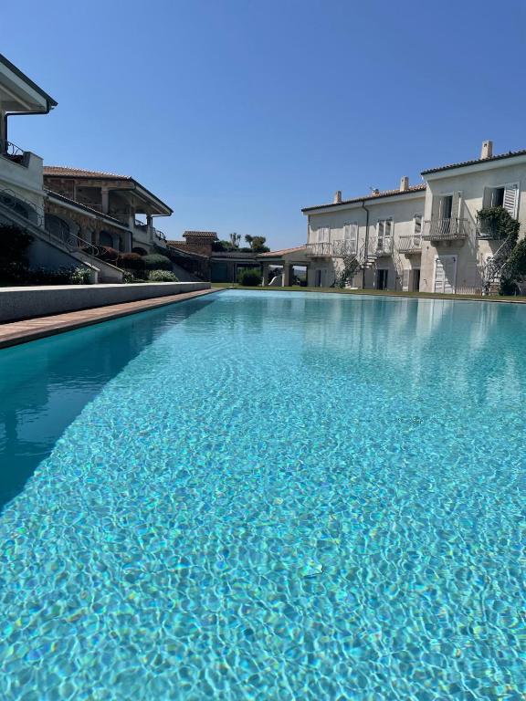 a swimming pool with blue water in front of some buildings at Sardinia Lighthouse Apartment in Palau