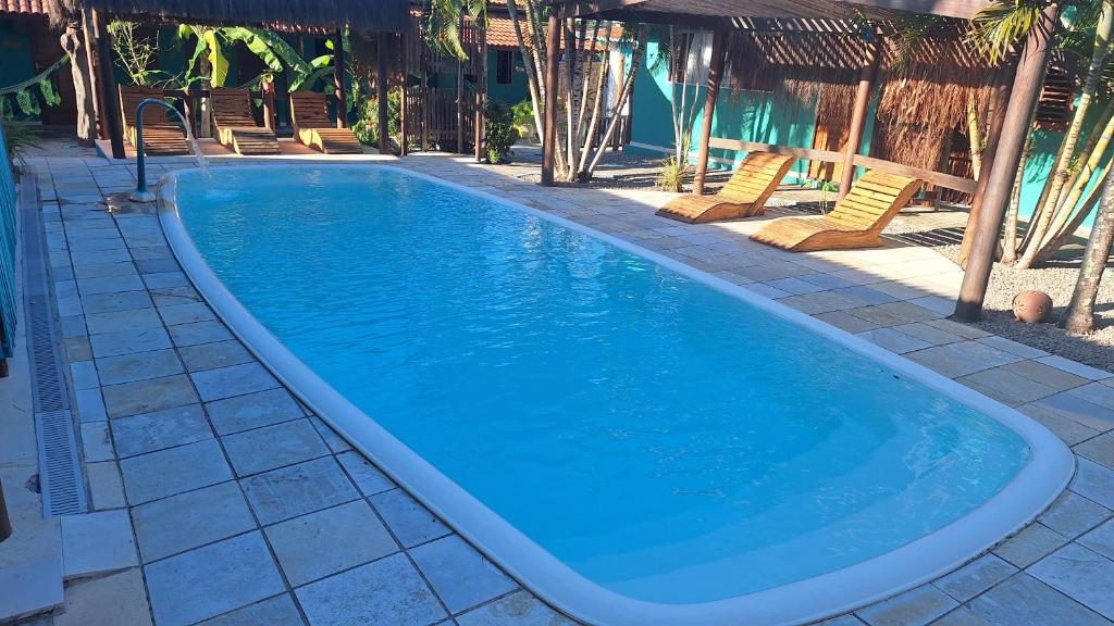 une grande piscine bleue avec des chaises autour dans l'établissement Hawaii Flats, à São Miguel do Gostoso