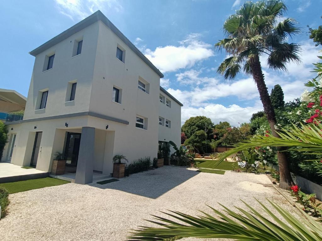 une maison blanche avec un palmier devant dans l'établissement Villa d'Exception à 20m Des Sablettes Plage, Côte d'Azur, à La Seyne-sur-Mer