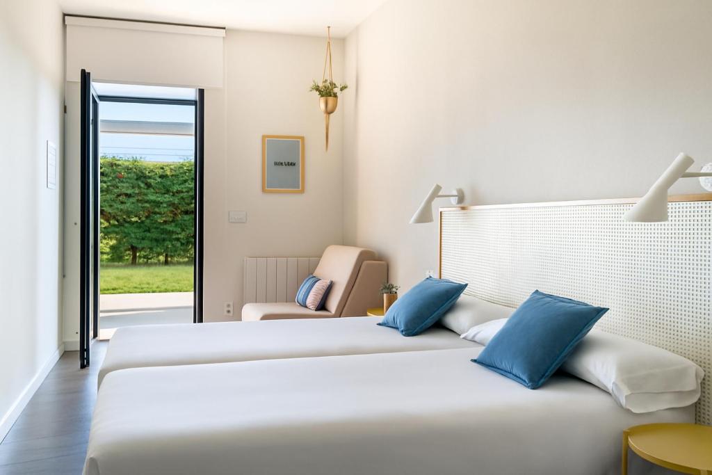 a hotel room with two beds and a chair at Langre Homely Rooms in Galizano