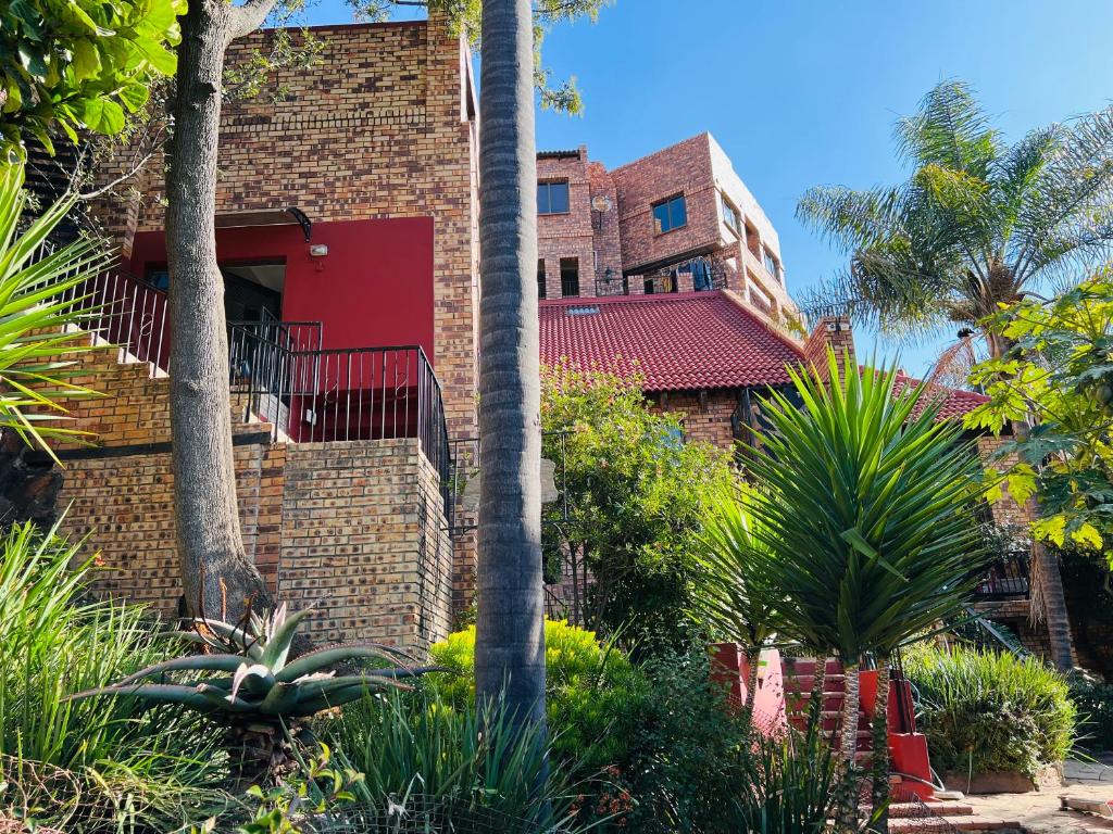 a red brick building with palm trees and plants at Melville Penthouse With Stunning Views in Johannesburg
