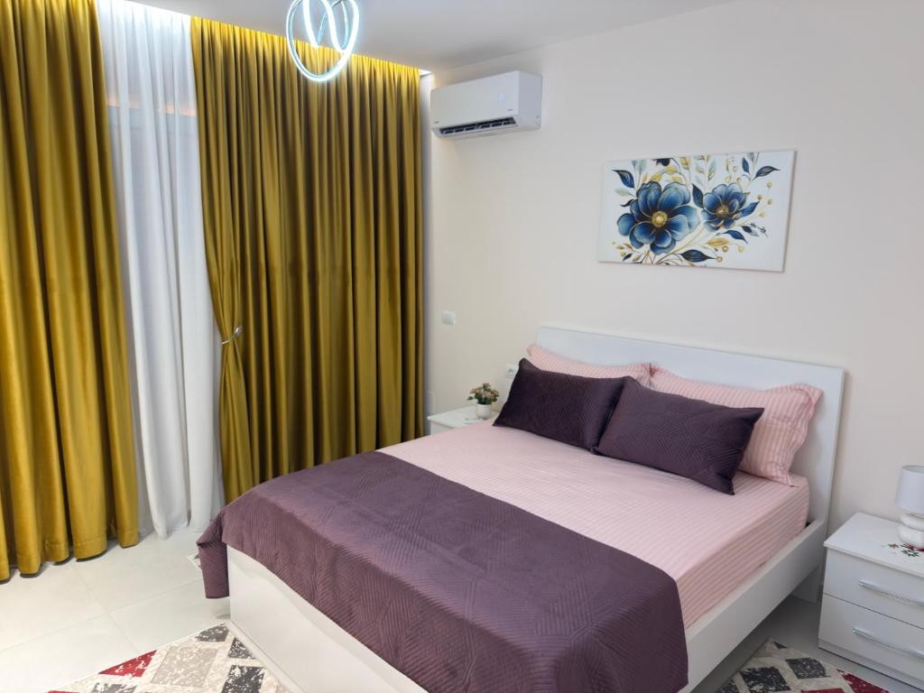 a bedroom with a bed and yellow curtains at City View Apartments in Durrës