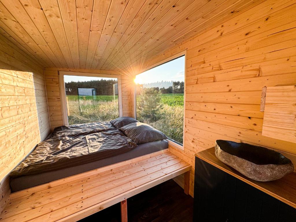 a bed in a wooden room with a window at Maringotka uprostřed ničeho in Třemošná