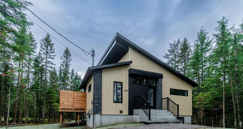 een klein huis met een zwart dak in het bos bij Villa Le Frigg spa swimming pool in Valcartier Station