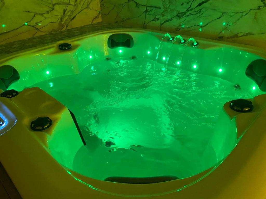 eine grüne Badewanne mit Beleuchtung in einem Badezimmer in der Unterkunft Masažinis baseinas senamiestyje in Klaipėda