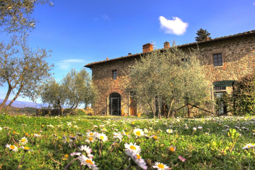 Agriturismo Casavecchia في فيليني فالدارنو: منزل حجري قديم مع حقل من الزهور