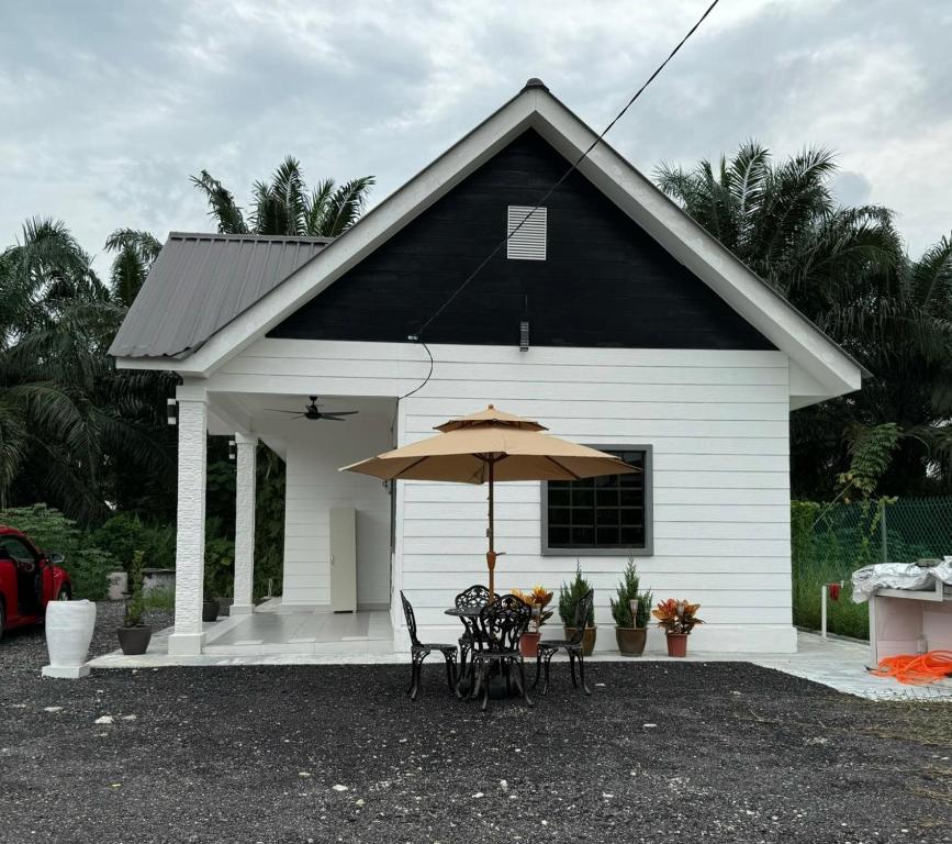 une petite maison blanche avec une table et un parasol dans l'établissement Pondok Selesa Homestay, à Shah Alam