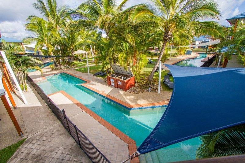 Una gran piscina con palmeras en un complejo turístico. en Palm Breeze Holiday Unit, en Agnes Water