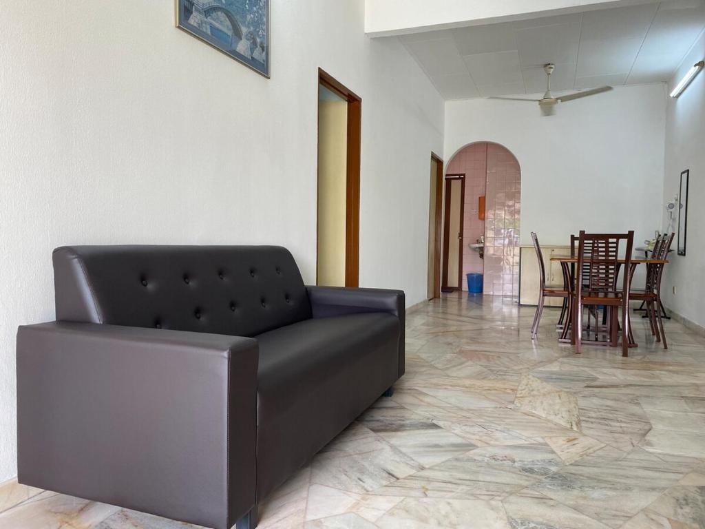 a black couch in a living room with a table at Staycation Taiping Homestay in Taiping