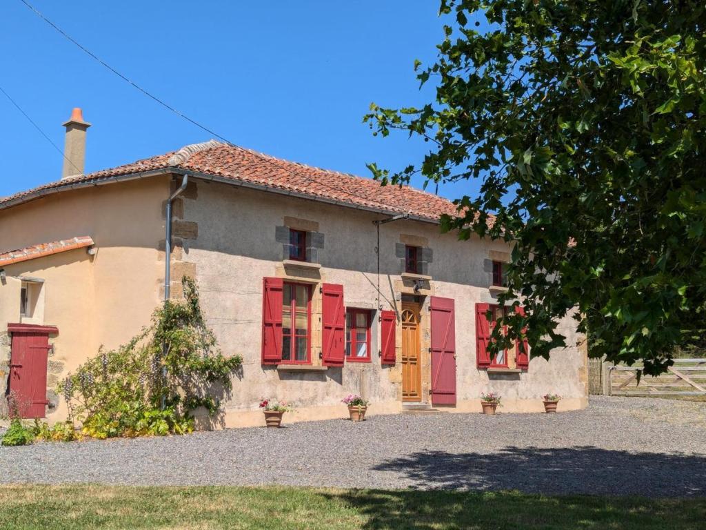 une vieille maison avec des volets rouges et un arbre dans l'établissement Charmante Maison de Campagne avec Piscine Chauffée en Charente - FR-1-653-278, à Abzac