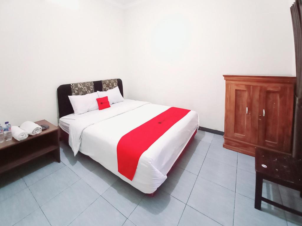 a bedroom with a bed with a red and white blanket at RedDoorz near BNS 3 Kota Wisata Batu in Malang