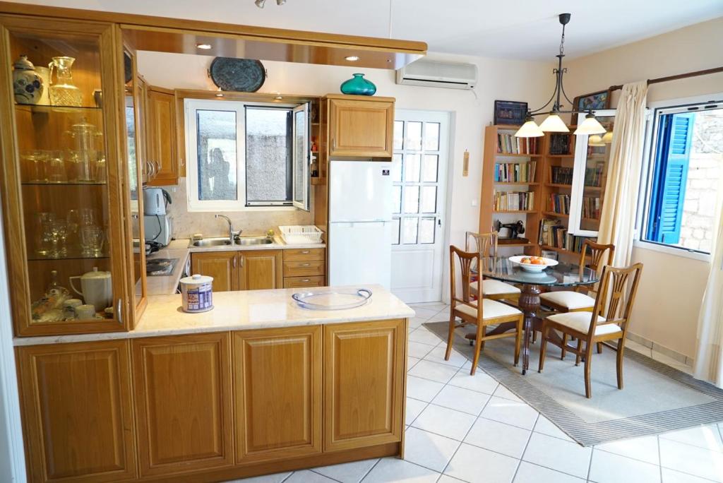 a kitchen with wooden cabinets and a table and a dining room at Villa Marika in Vathi