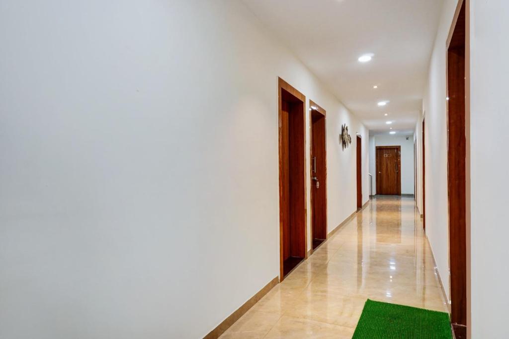 a hallway with white walls and a green rug on the floor at Super Hotel O KP Pride in Dehu