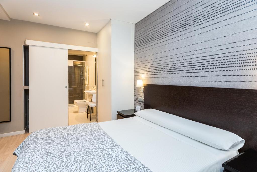 a bedroom with a white bed and a wooden headboard at Pensión Altair in San Sebastián