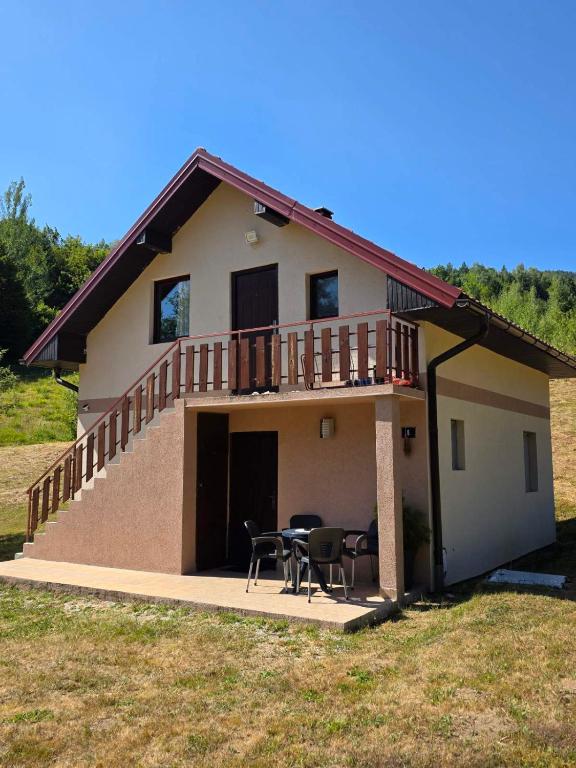 a house with a deck and a table and chairs at Camp Krivace in Pljevlja