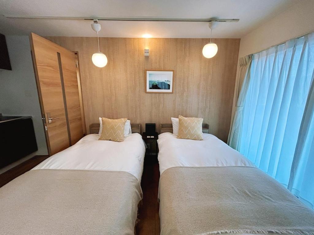 2 letti in una piccola camera con tende blu di 301 湘南 鵠沼海岸 サーフィンに最適なビーチ近くの独立型アパート a Fujisawa