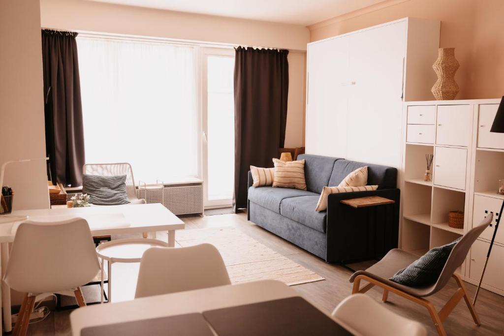 uma sala de estar com um sofá, uma mesa e cadeiras em Sea Side em Ostend