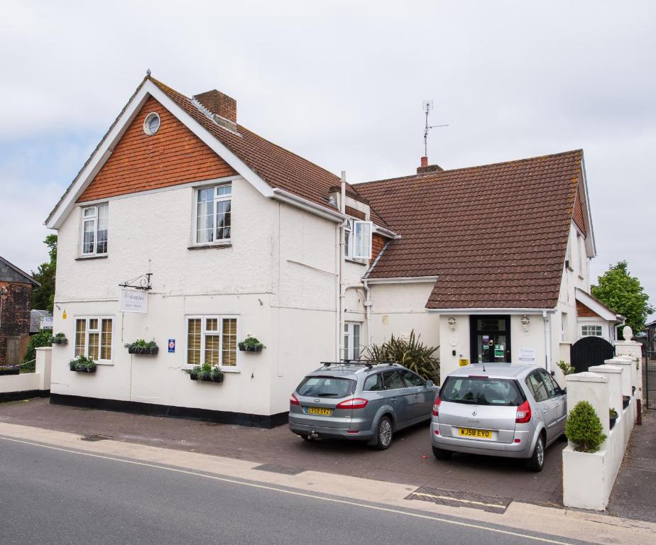 dois carros estacionados em frente a uma casa branca em The Maples em Hythe