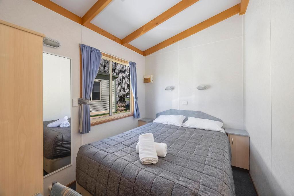 タマットにあるReflections Tumut Riverのベッドとタオル2枚のある寝室