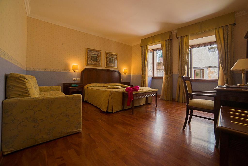 a bedroom with a bed and a couch and a chair at Hotel Filippeschi in Orvieto
