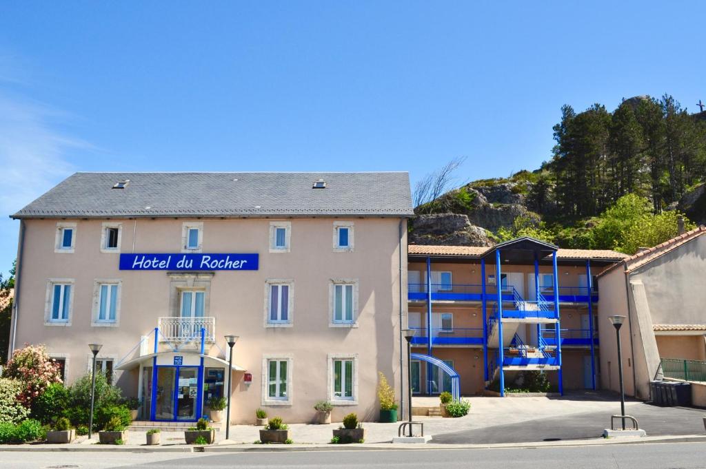 un bâtiment avec un panneau indiquant l'hôtel en pierre dans l'établissement Hotel Du Rocher, à Le Caylar