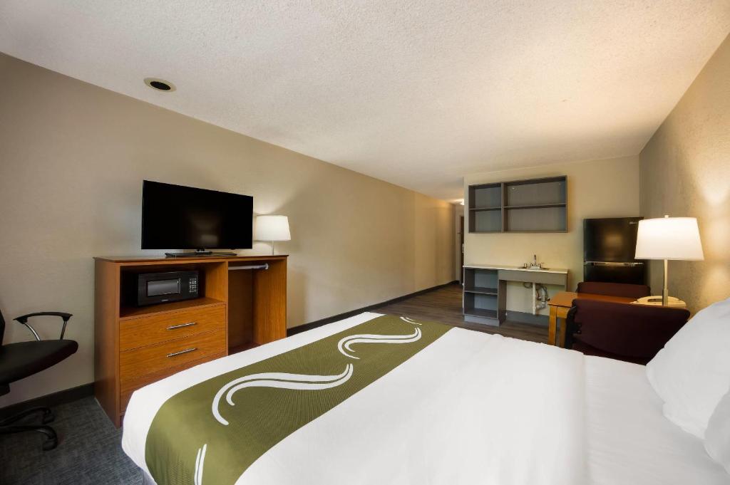 Una habitación de hotel con una cama y un televisor de pantalla plana. en Suburban Studios Canon City, en Canon City