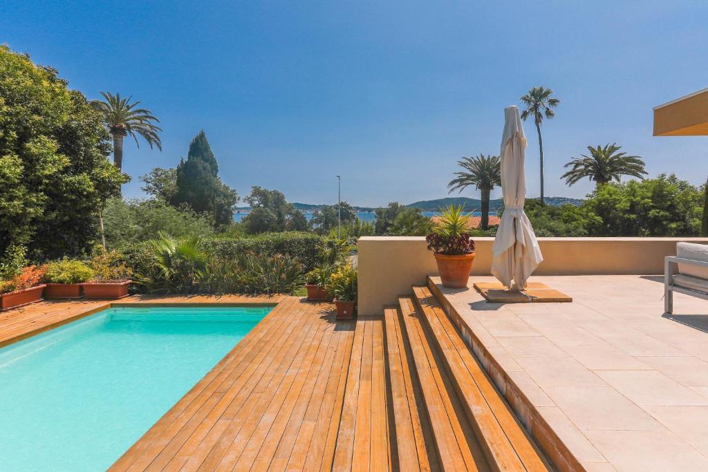 une piscine avec une terrasse en bois et un parasol dans l'établissement Villa Capitane, à Grimaud